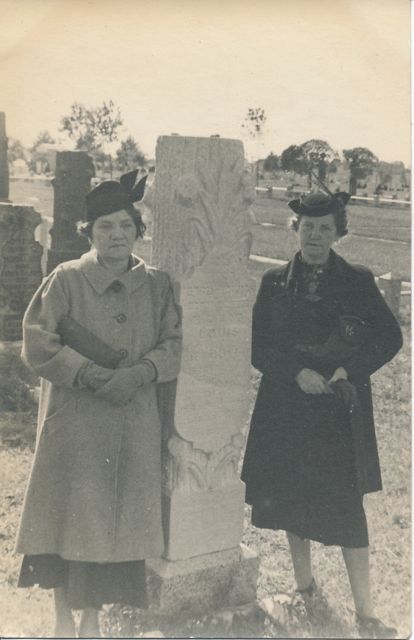 Gussie and
                        Regina standing alongside gravestone of Louis
                        Hertzberg