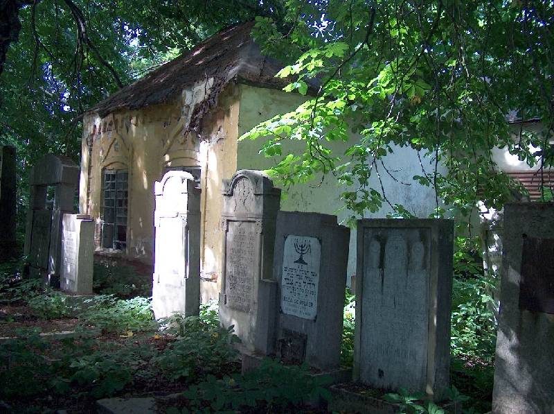 A small building behind rows of headstones