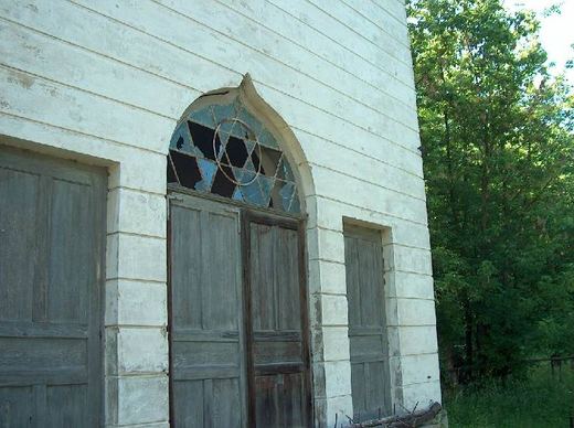 An arched window with a Star of David above the wooden doors of a cemetery building