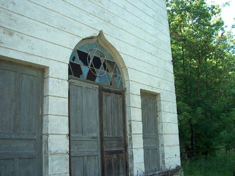 An arched window with a Star of David above the wooden doors of a cemetery building