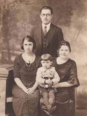Philip Simon (Pinchus Shadchan) standing, his wife Jennie Polsky Simon, mother Nechoma Platensky Shadchan (sister to Louis), and son Benjamin Morris Simon, circa 1924-1925. Philip's father and other Shadchan family members ran several businesses in Stavisht. His daughter Clara Simon Mattes, who submitted the photo, writes <q>They had a hardware store that sold everything including wagon wheels and just about anything needed. They also had a business where they would pay someone for the sole use of a small lake. They would then go there with hired help, put huge nets in the lake and take out all the fish, which they would then send (or go) to towns to sell. Another business was purchasing and selling horses. They owned a small house which my grandmother sold when they were leaving Russia.</q> <em>Note: Shadchan is the Hebrew term for <q>matchmaker.</q> Perhaps we have the Shadchan family to thank for our existence!</em>