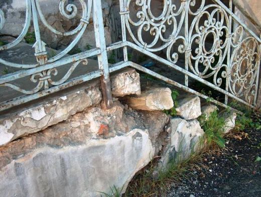 Broken stone steps under the wrought-iron railing