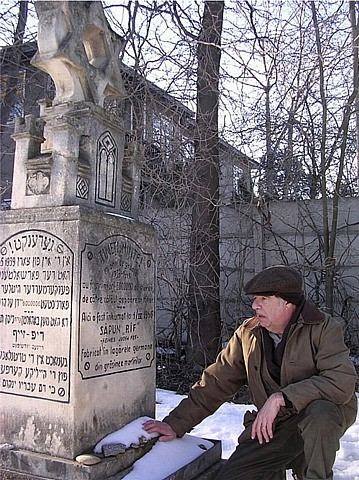 The Radauti Holocaust Memorial at the Jewish Cemetery, with a man beside it