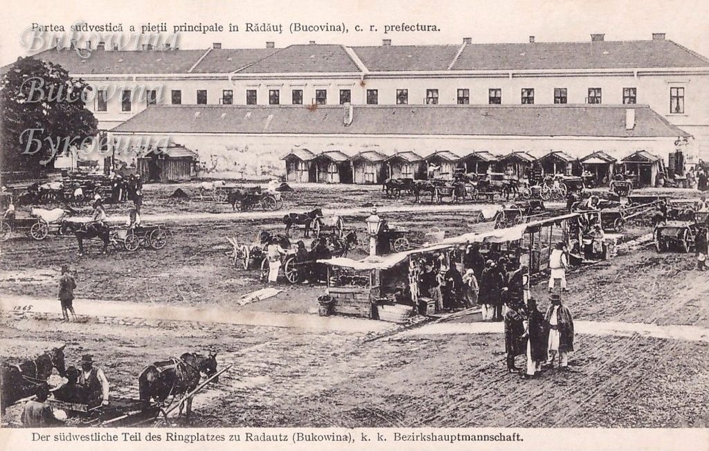 Market square with horse carts and canvas stalls in front of a long two-storey district office lined with wooden booths