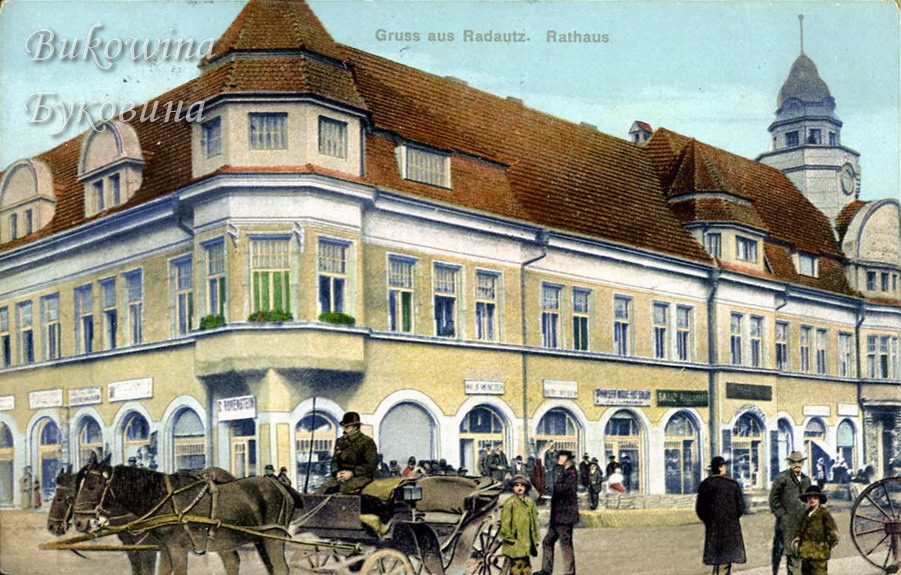 Coloured view of the town hall with a clock tower, a horse-drawn carriage and well-dressed people in front