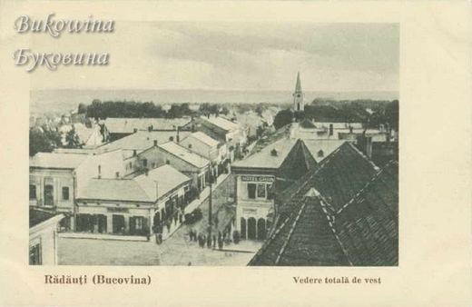 View over rooftops down a busy street with a sign reading Hotel, and a church spire rising in the distance