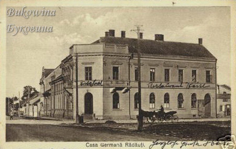 Two-storey corner building with hotel and restaurant lettering on the facade and a horse-drawn carriage