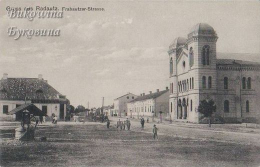 Domed temple at right on a broad street, a covered well and low house at left, children and people walking