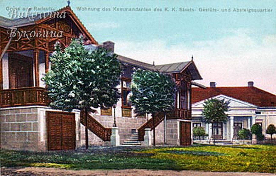 Coloured view of a carved wooden chalet-style house on a stone base beside a white house with a columned porch